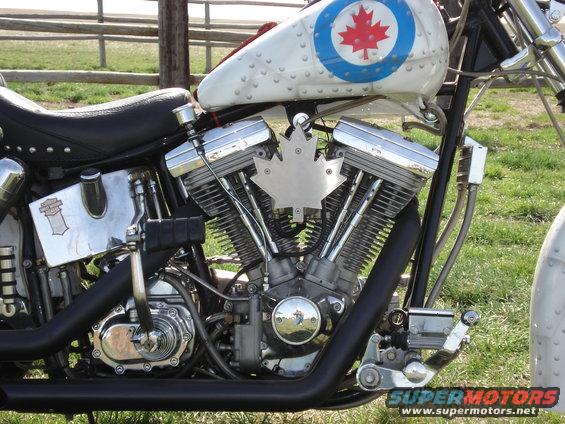 Motorcycle engine with chrome accents and a silver maple leaf emblem on the V-twin cylinders. Tank has a Canadian roundel