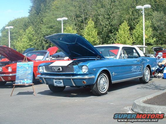 Blue 1965 Ford Mustang coupe, hood open, showing chrome wire wheels and side trim