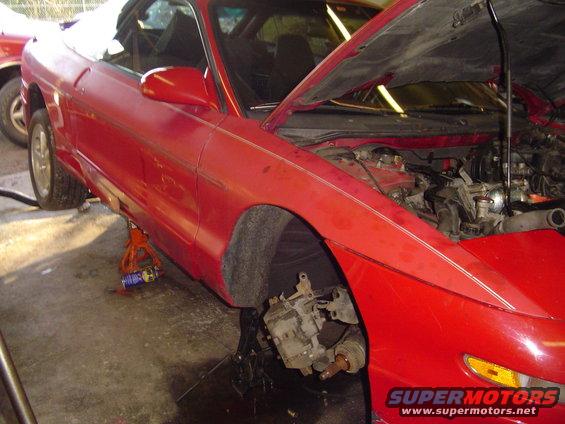 Red 1994 Ford Probe with front wheel removed and hood open