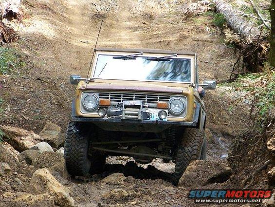 1968 Ford Bronco climbing a rocky, muddy trail, front view