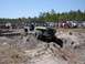 1989 Ford Bronco - A crowd watches as a modified Jeep navigates a challenging dirt obstacle during an outdoor event.