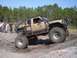 1989 Ford Bronco - This heavily modified truck is shown navigating a muddy terrain during an off-road event.