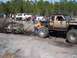 1989 Ford Bronco - Off-road vehicles navigate a muddy course with onlookers present.