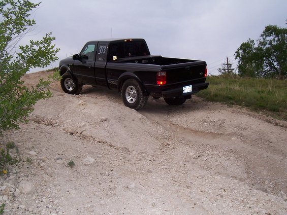 Black pickup truck with number 313 on the door driving on a dirt road