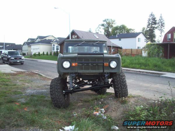 Green 1968 Ford Bronco lifted with large tires, front view