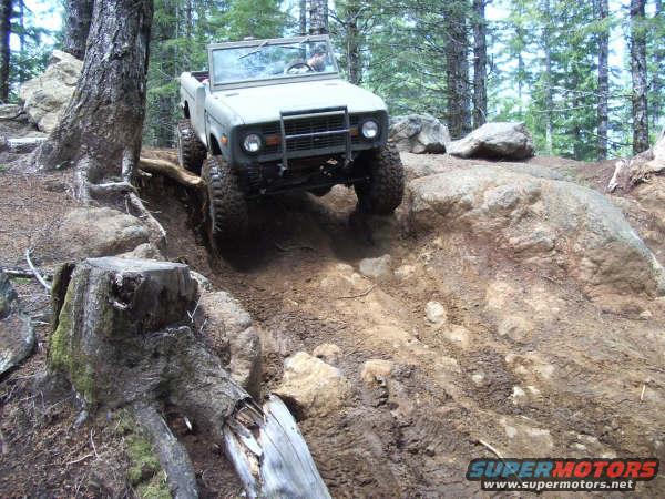 1968 Ford Bronco off-roading on a dirt trail with large rocks