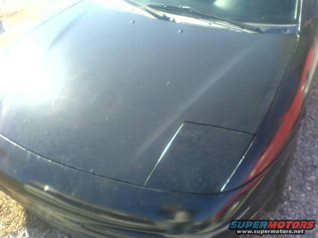 Black car hood with a closed pop-up headlight, viewed from a high angle