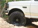 1996 Ford Bronco - A white 1996 Ford Bronco is shown off-road, with its front tire in dirt.