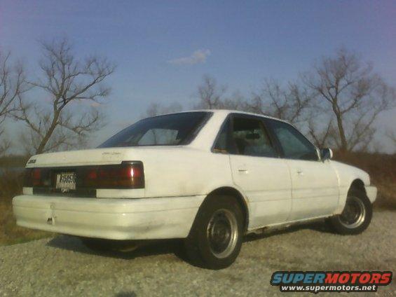 White sedan from the rear, showing a license plate and taillights