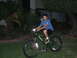 1988 Ford Bronco - A young boy wearing a helmet rides a green Specialized bicycle at dusk, with the front light illuminated.
