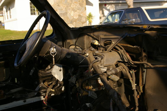 1986 Ford Bronco interior showing disassembled dashboard and steering wheel, with another Bronco visible outside