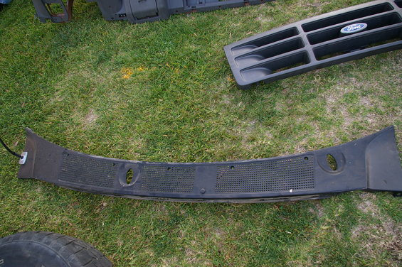 Black Ford grille with oval emblem and black dashboard trim piece on grass