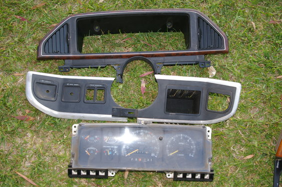 Dashboard trim and instrument cluster laid out on grass