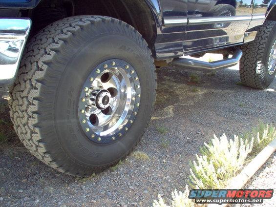 Close-up of a 1995 Ford Bronco's front wheel with aftermarket rims and side step
