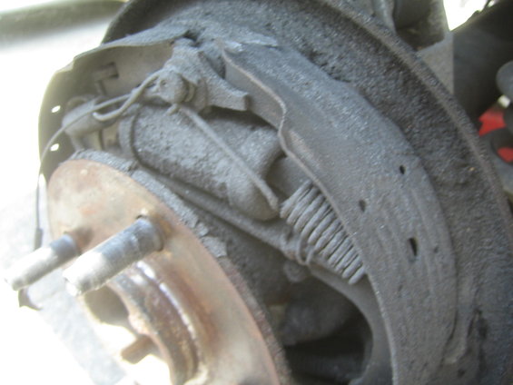 Close-up of a dusty rear drum brake assembly with brake shoes and springs