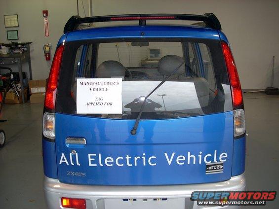 Blue electric vehicle with "All Electric Vehicle" text on the rear, "ZX40S" model designation, and a "MANUFACTURER'S VEHICLE TAG APPLIED FOR" sign