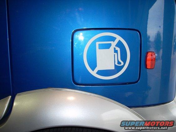Blue vehicle fuel door with a white no gas pump symbol sticker. Silver fender flare visible below