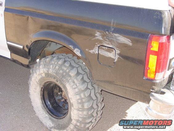 Close-up of a dented rear quarter panel and large off-road tire on a Ford Bronco