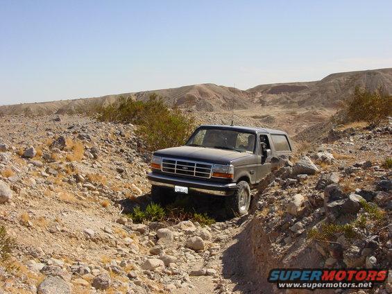 1994 Ford Bronco driving on a rocky trail in a desert area