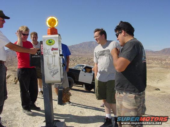 Group of people near a payphone with a two-tone truck in the background