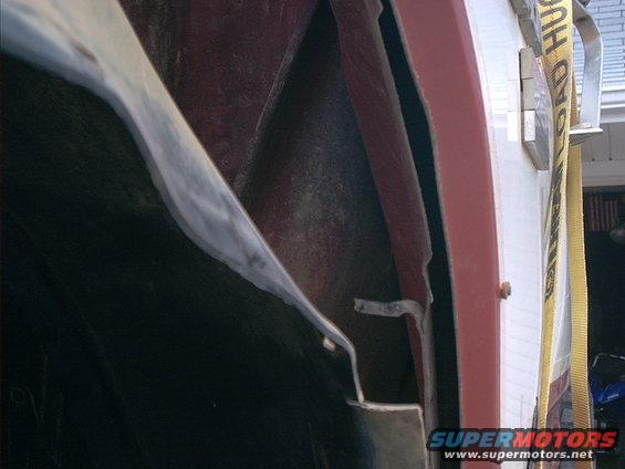 1986 Ford Bronco fender well interior with red body panel and yellow strap