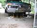 1977 Ford F-150 - A green 1977 Ford F-150 truck is raised on jack stands for maintenance, revealing its front undercarriage and a winch.