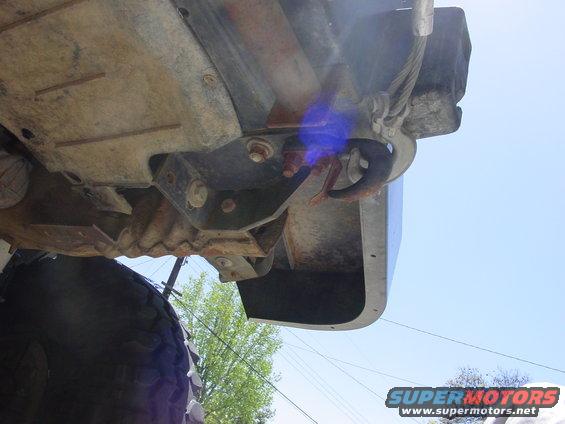 Underside view of a vehicle frame with a tow hook and cable attached