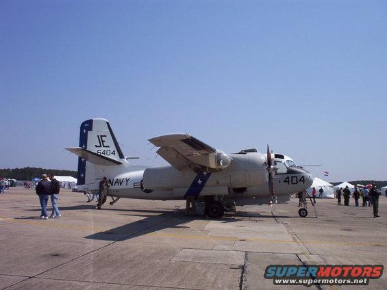 Grumman E-1 Tracer aircraft with 'NAVY' and 'JE 6404' markings on tarmac