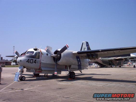 Gray twin-engine turboprop aircraft with red and white striped propellers, marked with '404 E' on the nose
