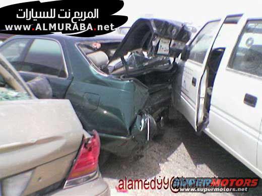 Wrecked green car's rear end crushed, seen from side