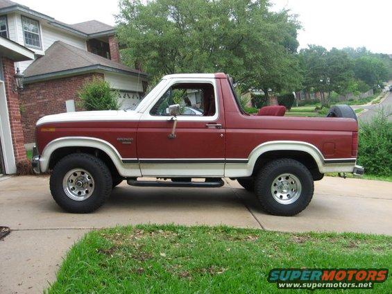 Red and white Ford Bronco parked on a driveway, side view