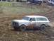 2001 Dodge 1500 - A white SUV with a brush guard drives through a muddy course with other vehicles in the background.