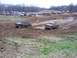 2001 Dodge 1500 - Pickup trucks navigate a muddy track during a race event, with spectators gathered in the background.