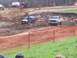 2001 Dodge 1500 - Trucks navigate a muddy course during an event, with spectators and equipment visible in the background.