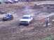 2001 Dodge 1500 - A white SUV navigates a muddy track during an off-road event, with a flagger signaling.