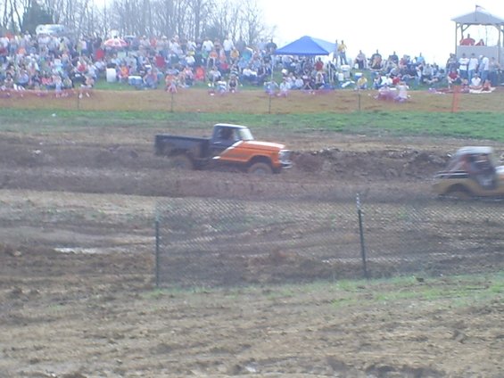 Orange and black pickup truck stuck in mud, side view