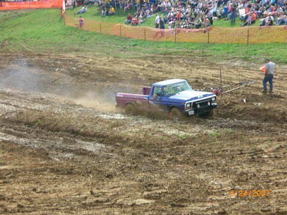 Blue and purple pickup truck stuck in mud, 1980s body style