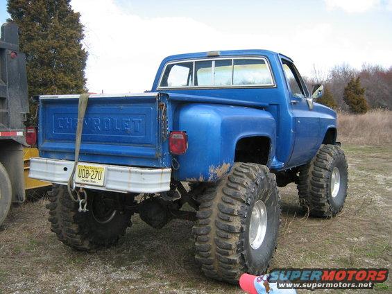 Blue Chevrolet pickup truck with oversized tires and lifted suspension, rear view