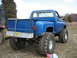 1990 Ford Bronco - This lifted Chevrolet pickup truck features massive off-road tires and a bright blue paint job, seen from the rear.