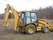 1990 Ford Bronco - A yellow Caterpillar backhoe loader sits in a field, its loader arm extended.