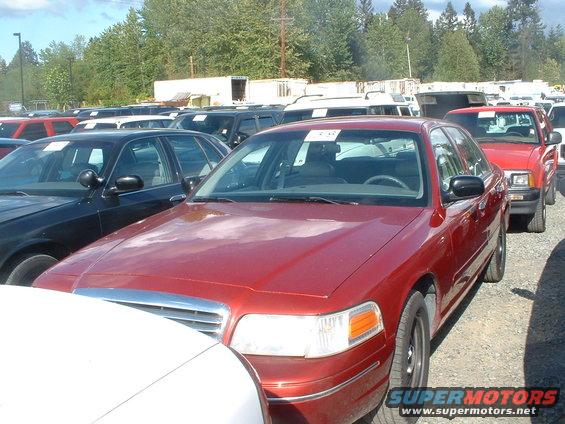 Red 2000 Ford Crown Victoria sedan parked in an outdoor lot with other vehicles