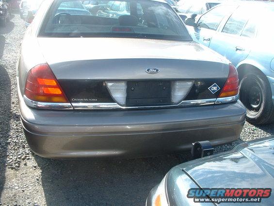 Rear of a 2000 Ford Crown Victoria, tan color, with a black trim panel and a CNG sticker