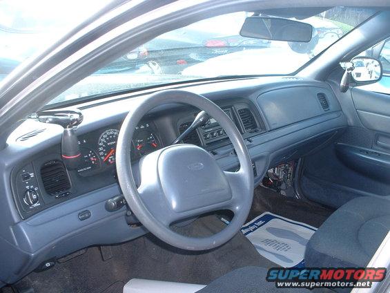 Gray dashboard and steering wheel of a 2000 Ford Crown Victoria, showing the instrument cluster and center console