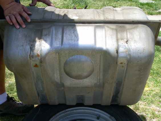 fuel tank being held by hands, resting on a tire