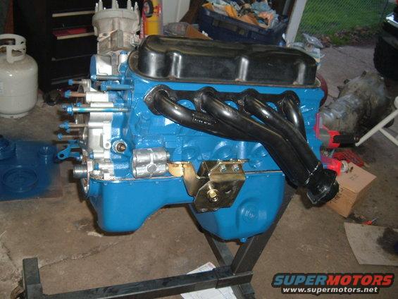 engine on stand, blue block, black headers, carburetor on top