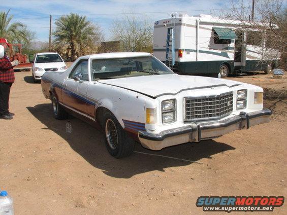 White pickup truck with blue and red stripes, front view. Appears to be a 1977 Ford Ranchero