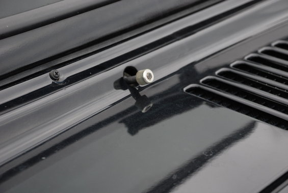 Close-up of hood latch mechanism on black vehicle hood with vent detail