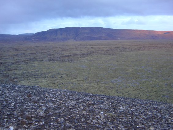 Vast, barren landscape with rolling hills and a cloudy sky