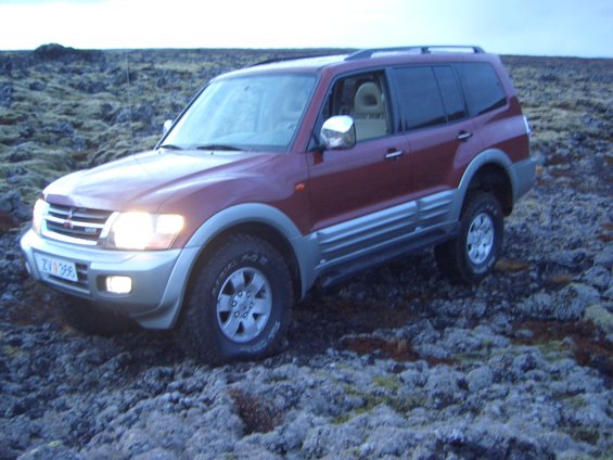 Red Mitsubishi Pajero parked on rocky terrain