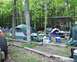 1991 Ford Bronco - A wooded campsite is set up with multiple tents and picnic tables, suggesting a recreational outdoor gathering.